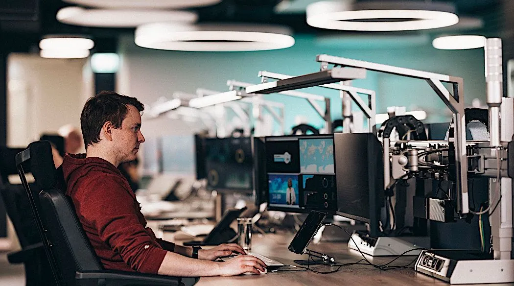 Cybersecurityspecialist aan een individueel verstelbare SOC-werkplek met monitorarmen en verblindingsvrije taakverlichting